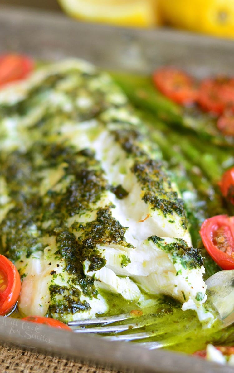 Lemon Herb Butter Cod with Asparagus and Tomatoes in a baking dish with a fork 