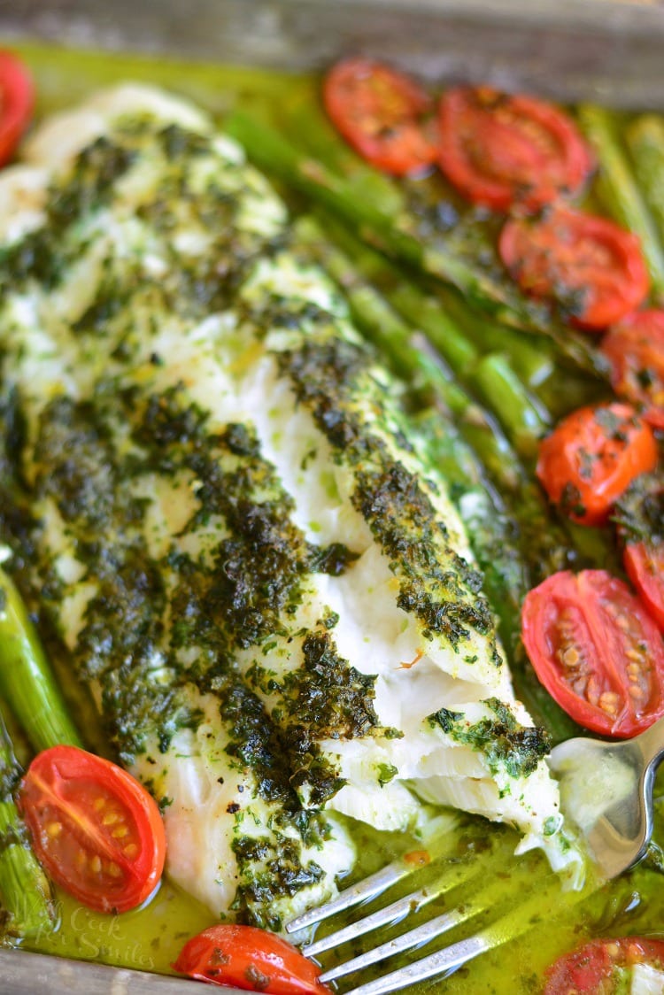 Lemon Herb Butter Cod with Asparagus and Tomatoes in a baking dish with a fork 