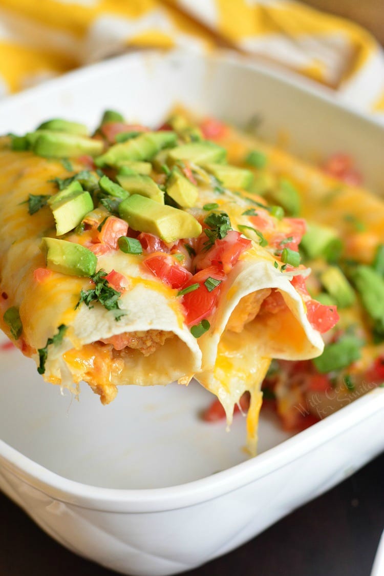 Western Omelet Breakfast Enchiladas in a casserole dish being lifted out with a spatula 