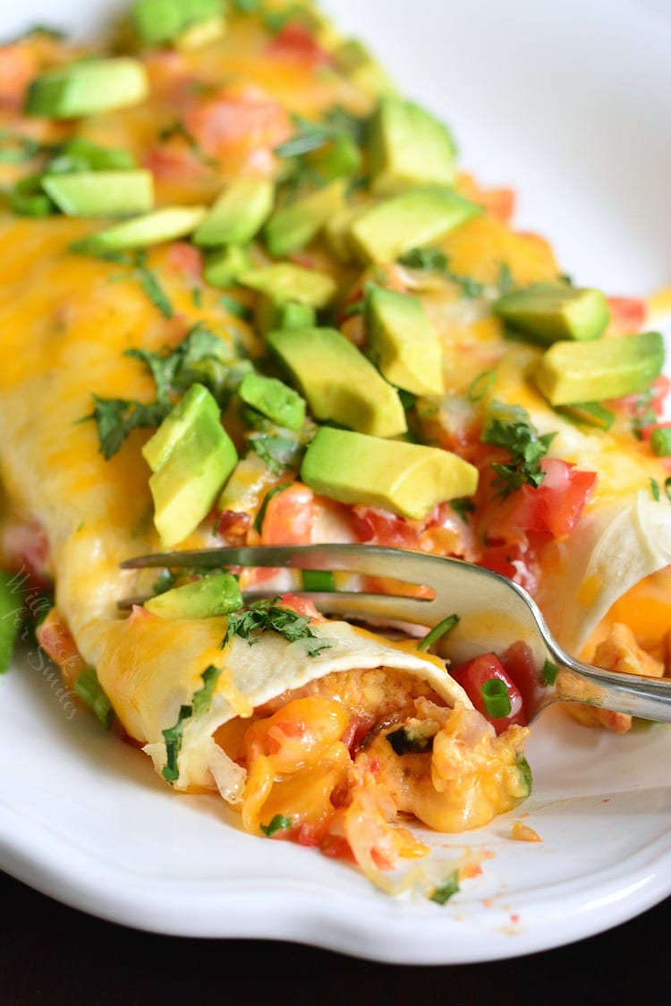 Western Omelet Breakfast Enchiladas on a plate cutting a bite out with a fork 