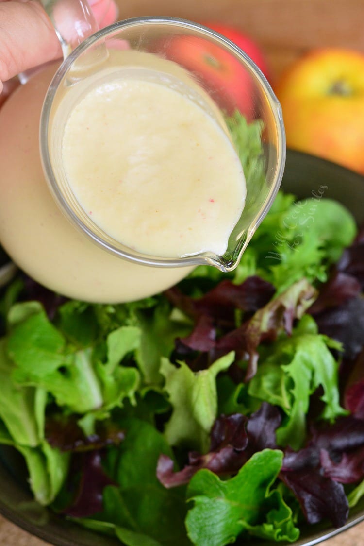 pouring homemade Apple Vinaigrette over a salad 