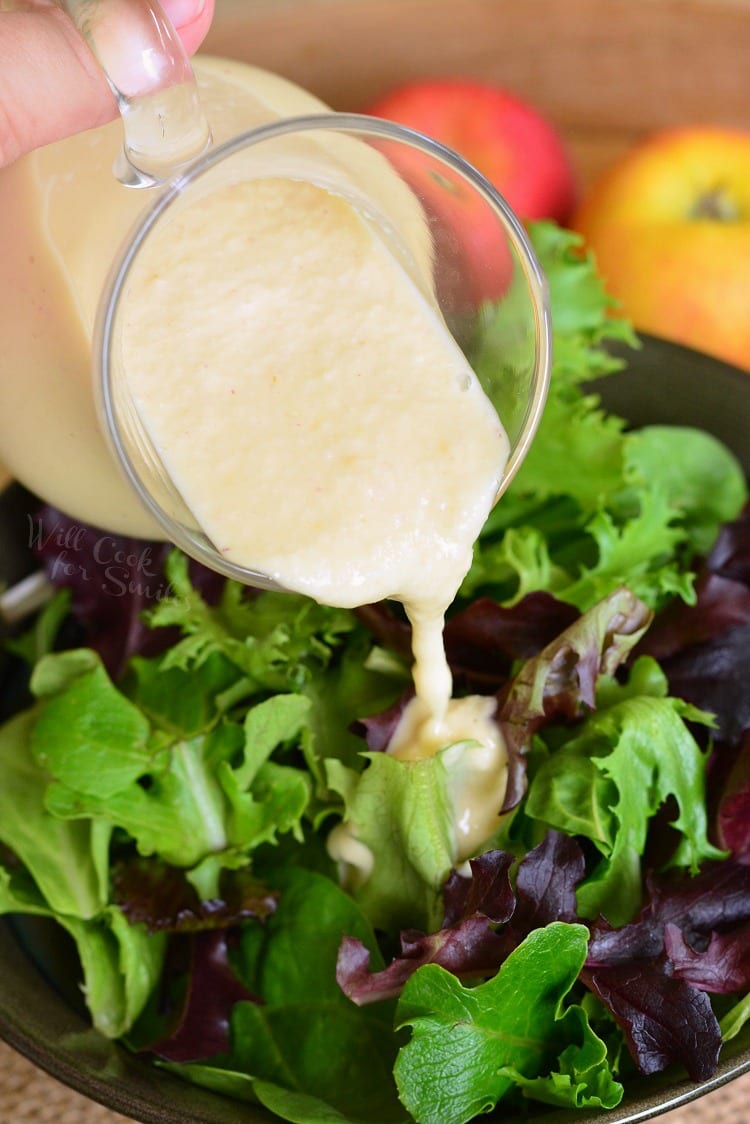 pouring homemade Apple Vinaigrette over a salad 