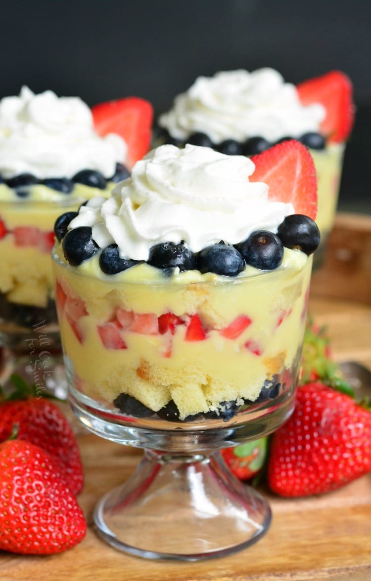 Easy Coconut Berry Trifle in a glass serving bowl on a cutting board with a strawberries 