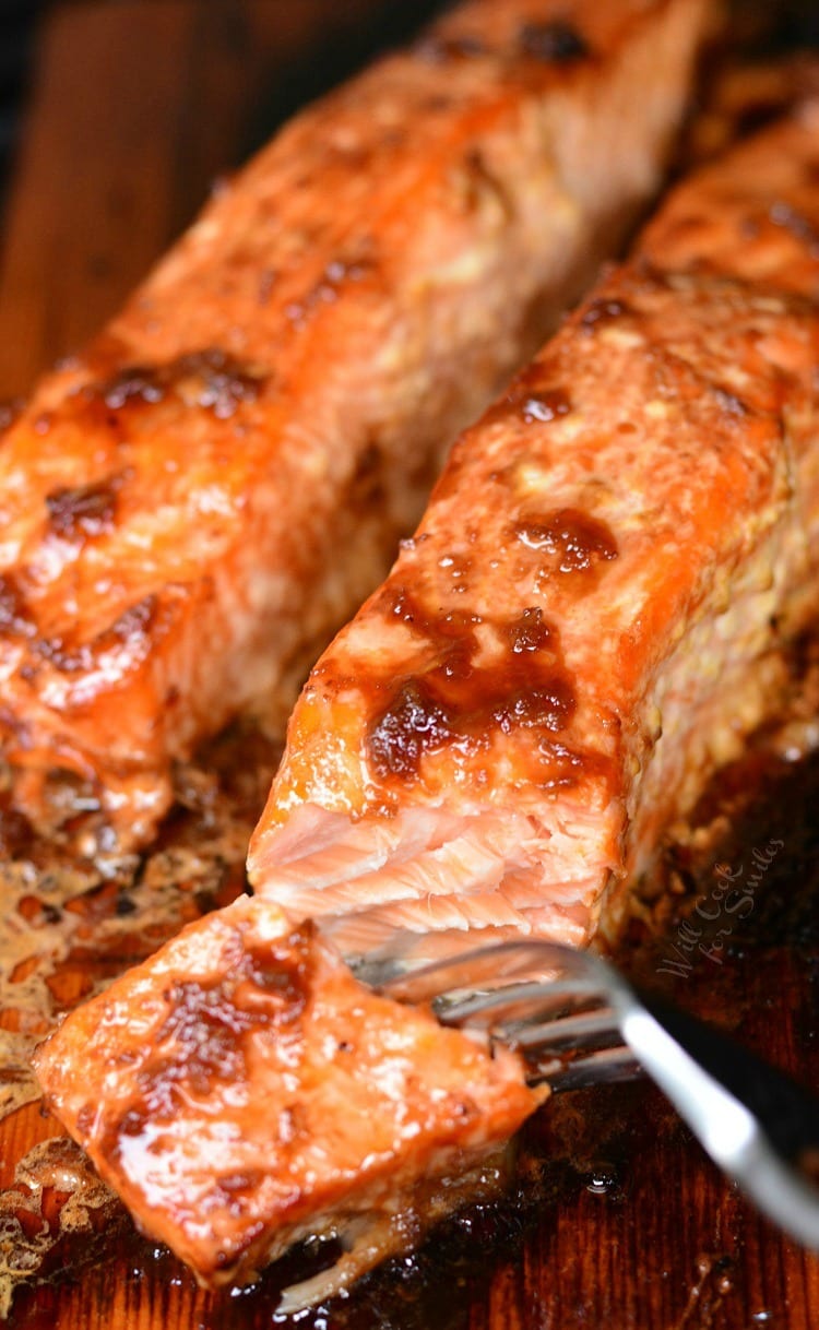 Honey Ginger Cedar Plank Salmon on a cutting board with a piece on a fork 