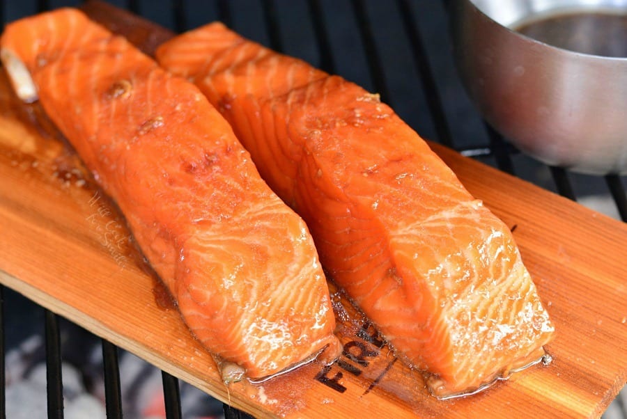 two pieces of salmon on a cedar plank on the grill 
