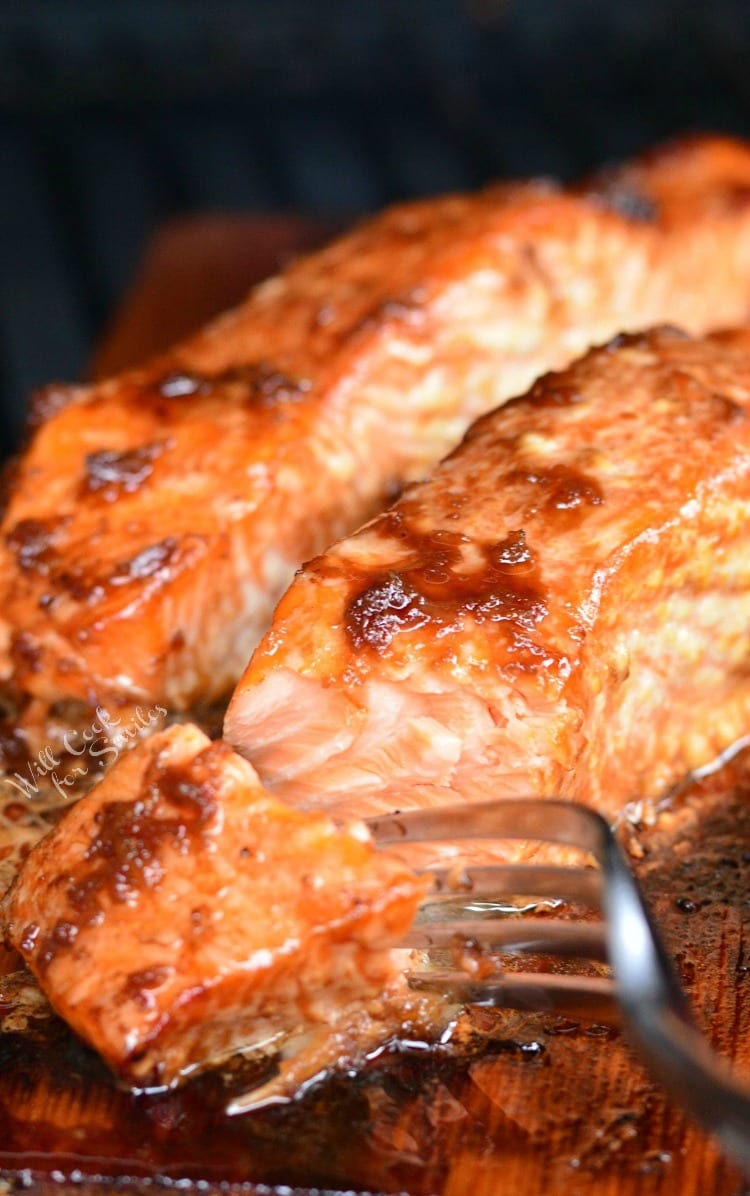 Honey Ginger Cedar Plank Salmon cooked and on the cedar plank with a fork 