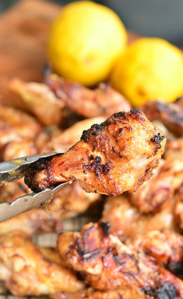 Holding Lemon Pepper Grilled Chicken Wings with tongs 