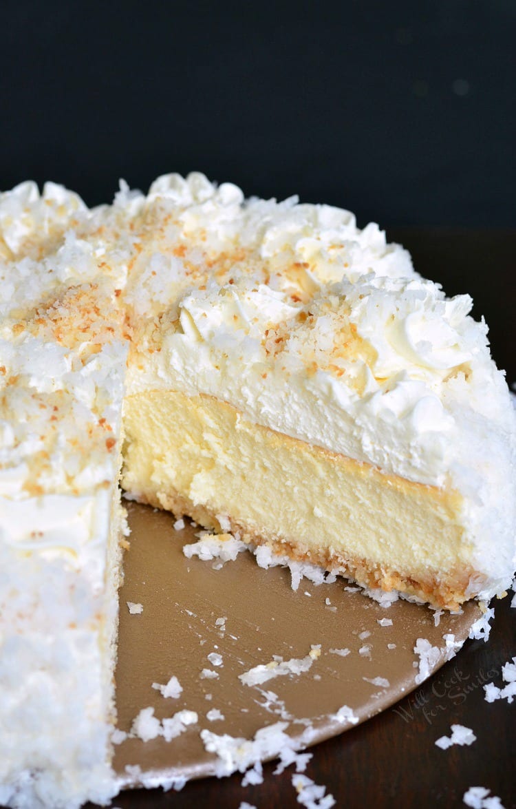 ULTIMATE Coconut Cheesecake with a slice missing on a table 