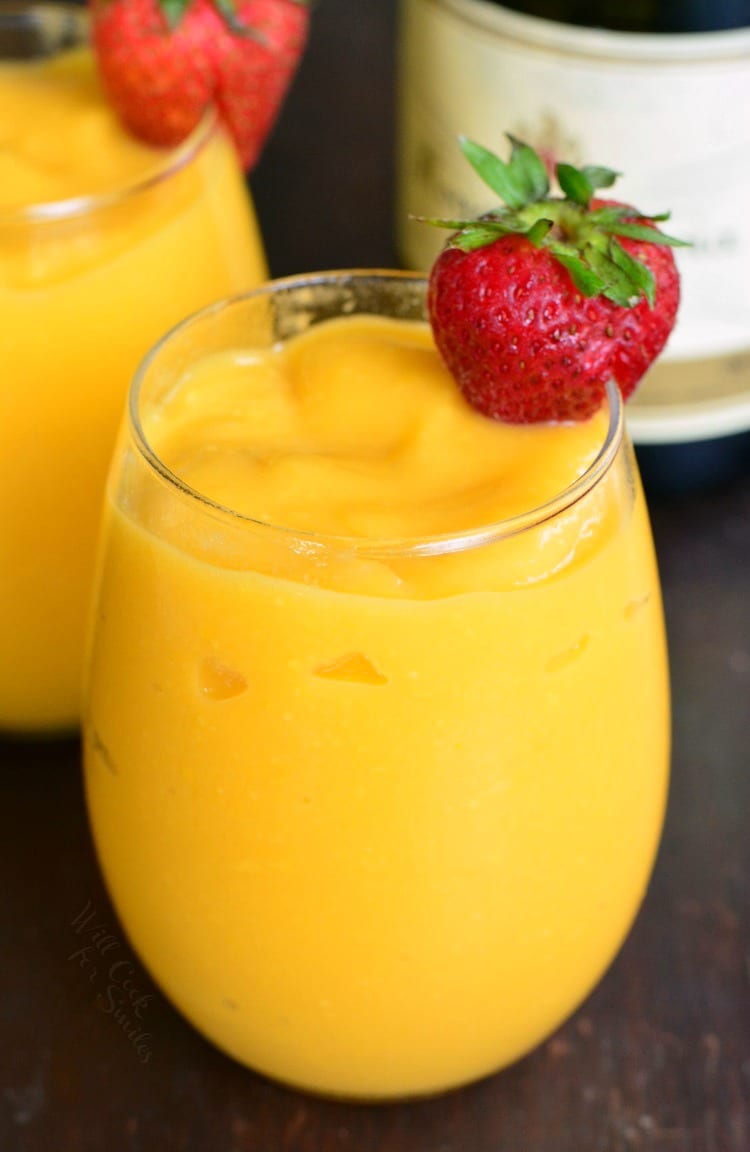 Mango Champagne in a champagne glass with a strawberry on the rim.