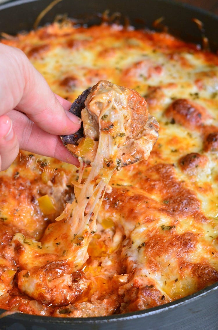 dipping a chip in Cheesy Meatball Dip recipe