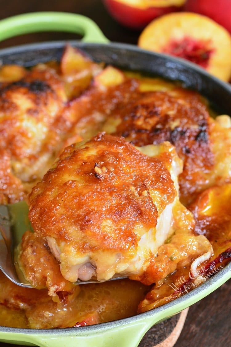 pulling out one chicken thigh out of the pan with a silver spatula 