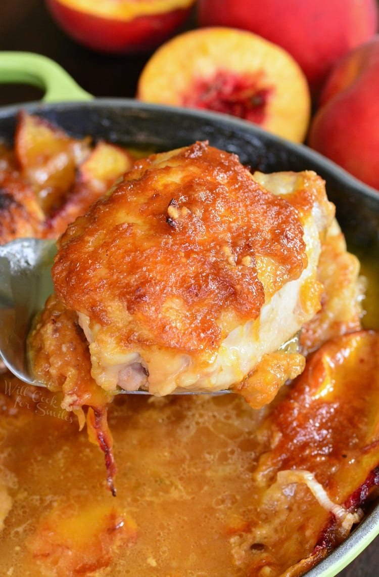 close up of chicken thigh on the spatula with peaches on the background 