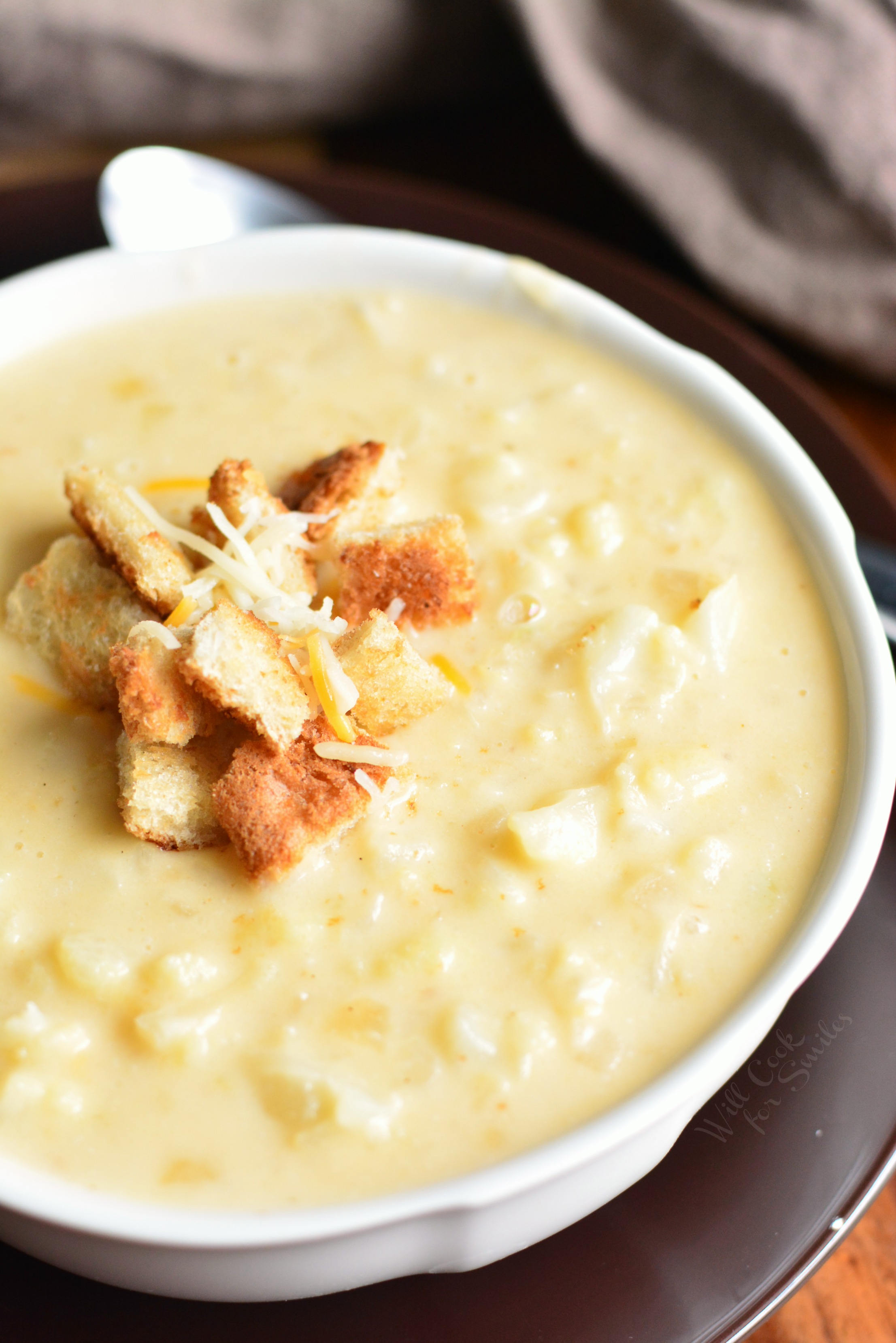 Cauliflower Cheese Soup in a bowl with croutons and cheese on top 