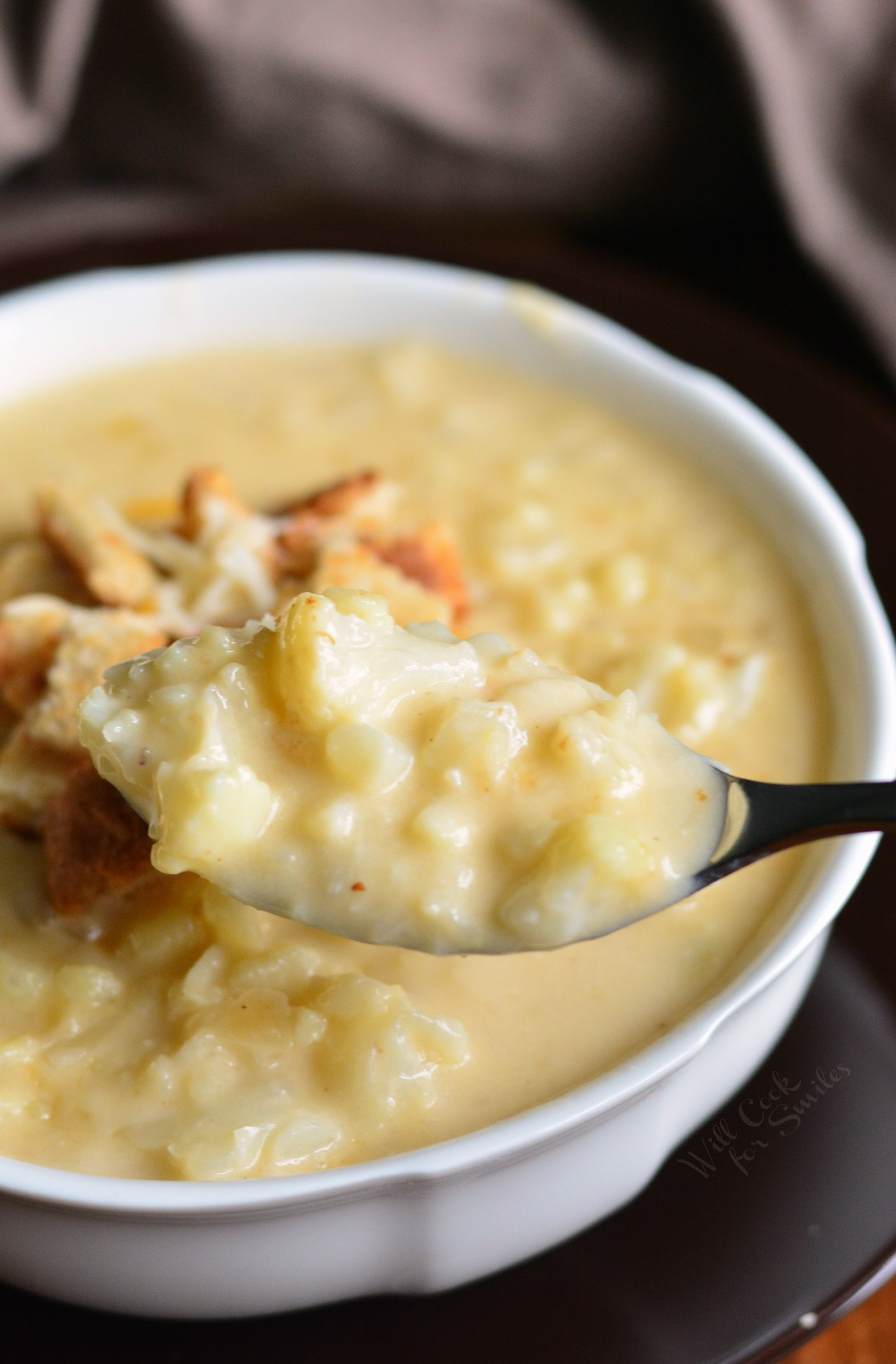 Cauliflower Cheese Soup in a bowl with a spoon scooping some out 