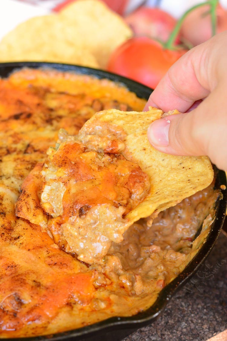 Creamy Beef Taco Dip in a pan with a chip scoping some out