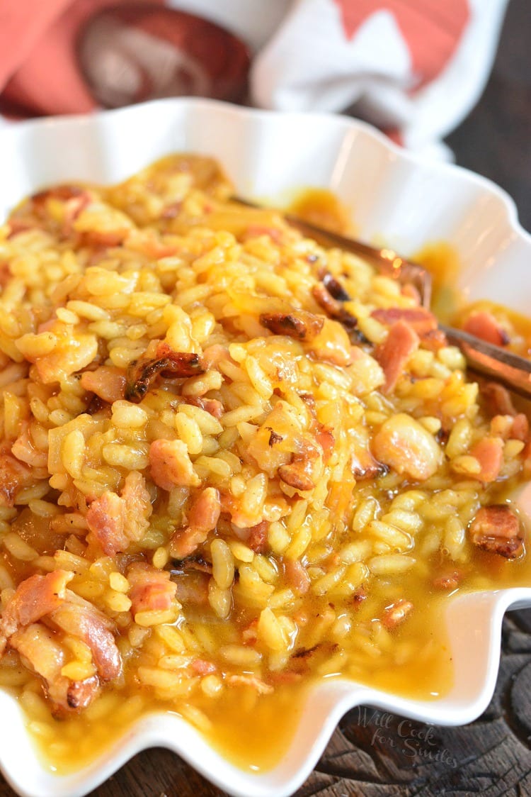 pumpkin bacon risotto in a white bowl with a fork.