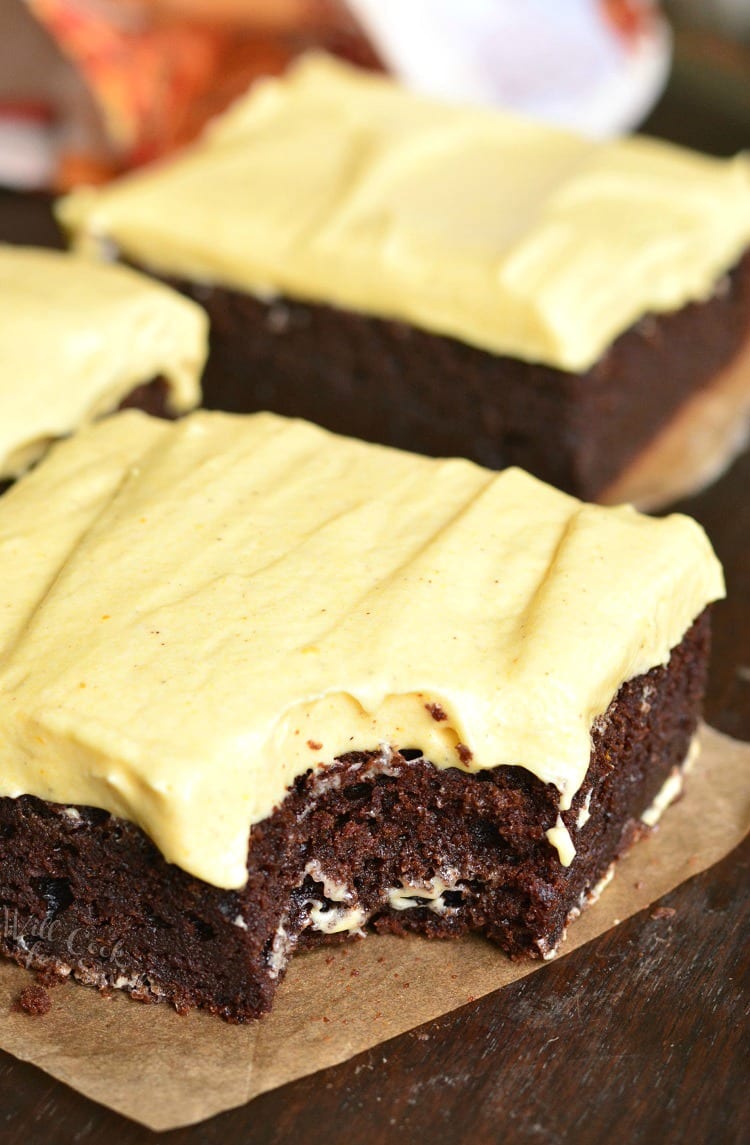 Frosted Pumpkin Brownie on a parchment paper with bite taken out 