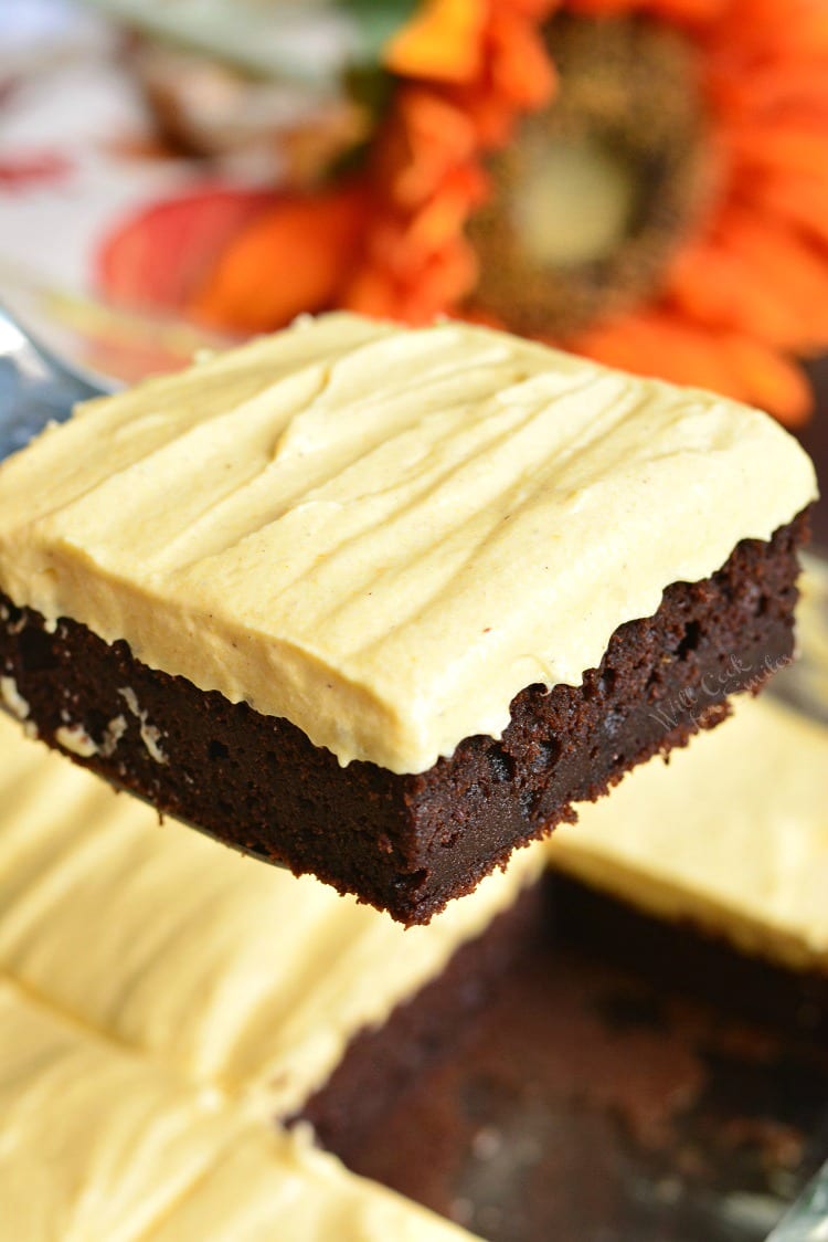 Frosted Pumpkin Brownies being lifted out pan