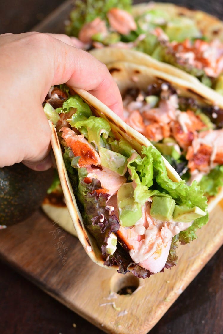 Easy Baked Salmon Tacos picked up in my hand with 2 other tacos in the background 