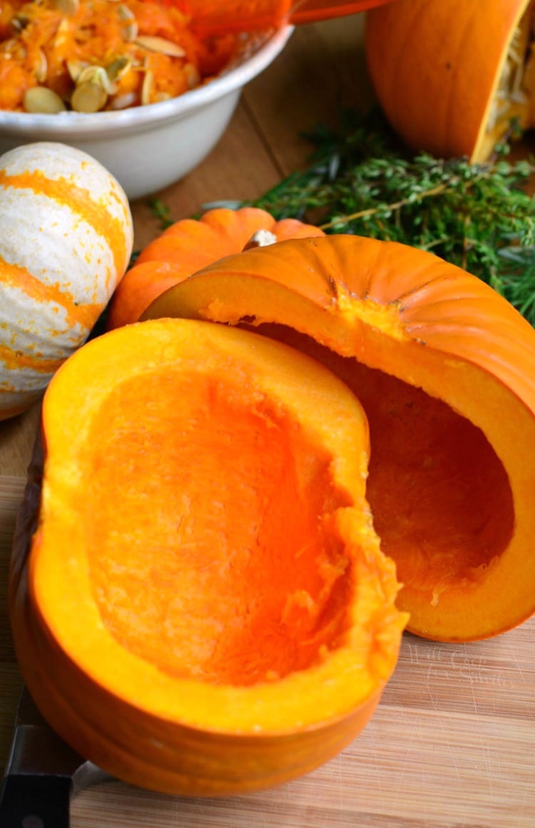 pumpkin cut in half with seeds removed bowl of seeds in the background 