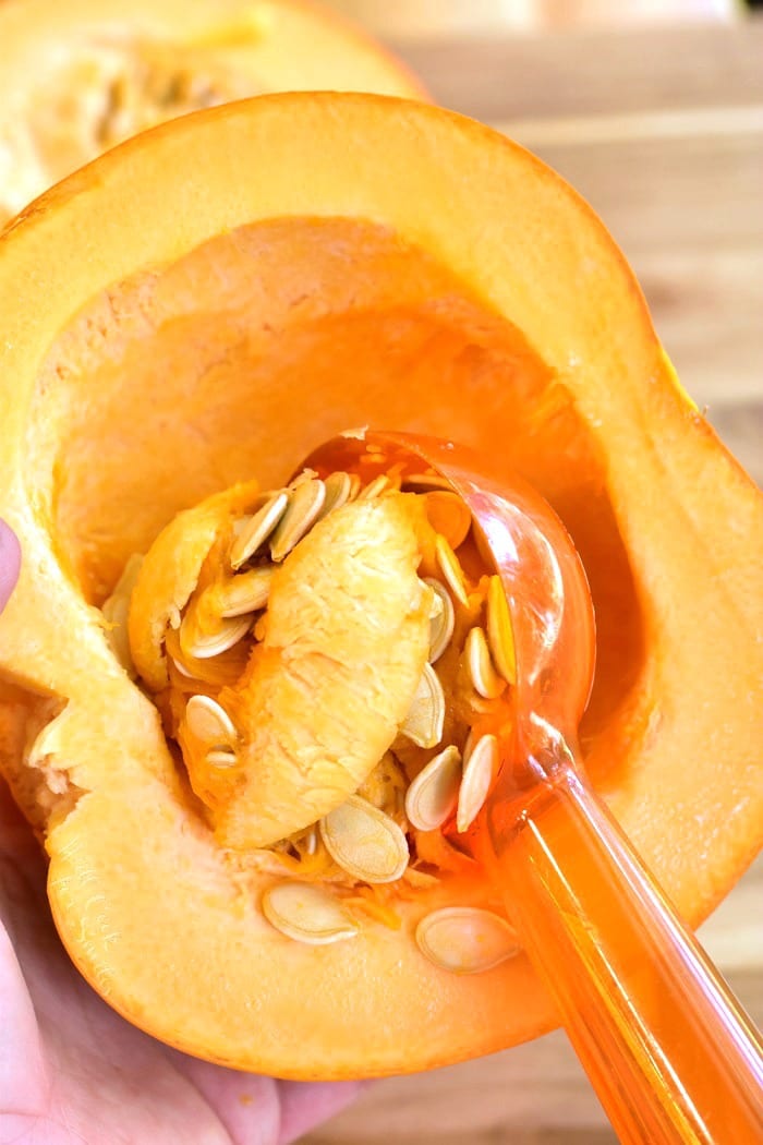 Scooping out seeds and membrane from pumpkin with a scoop
