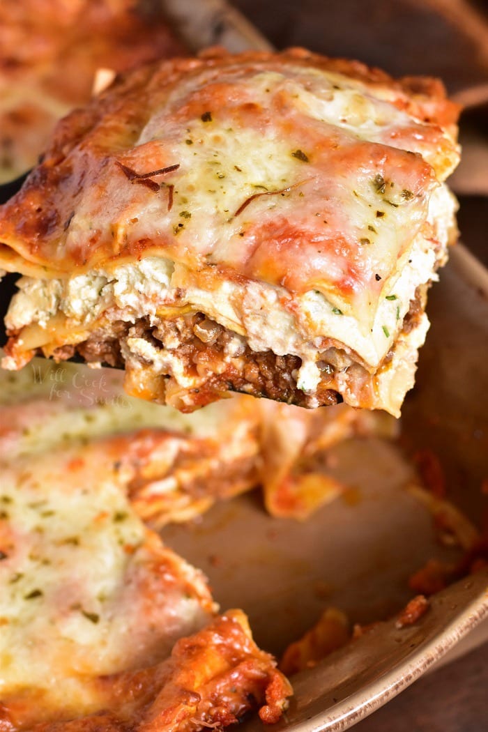 The BEST Lasagna in a baking pan lifting it out with a  spatula 