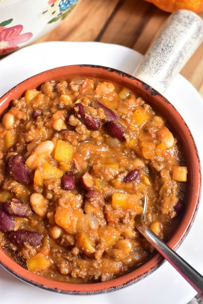 Pumpkin Chili in a bowl a with a spoon on a wood table 