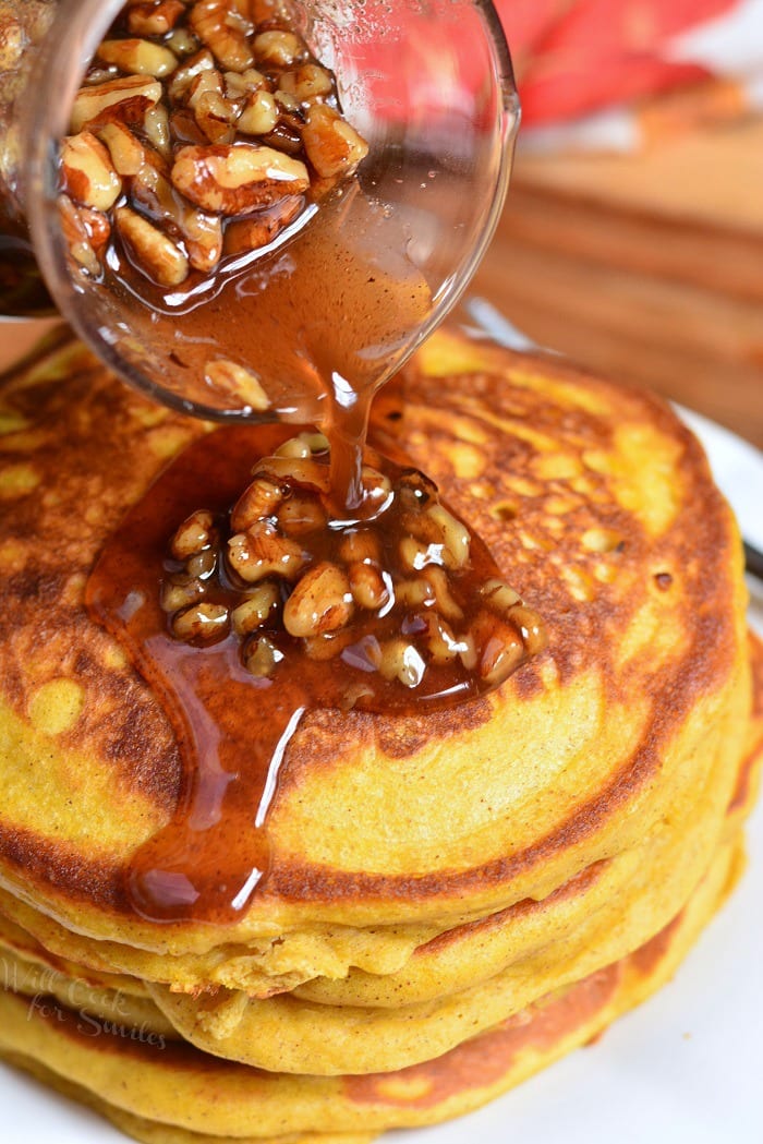 pouring syrup over Pumpkin Pancakes on a plate 