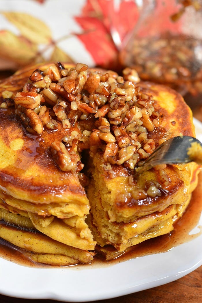 Soft and Fluffy Pumpkin Pancakes with Cinnamon Pecan Syrup on a plate with a fork 