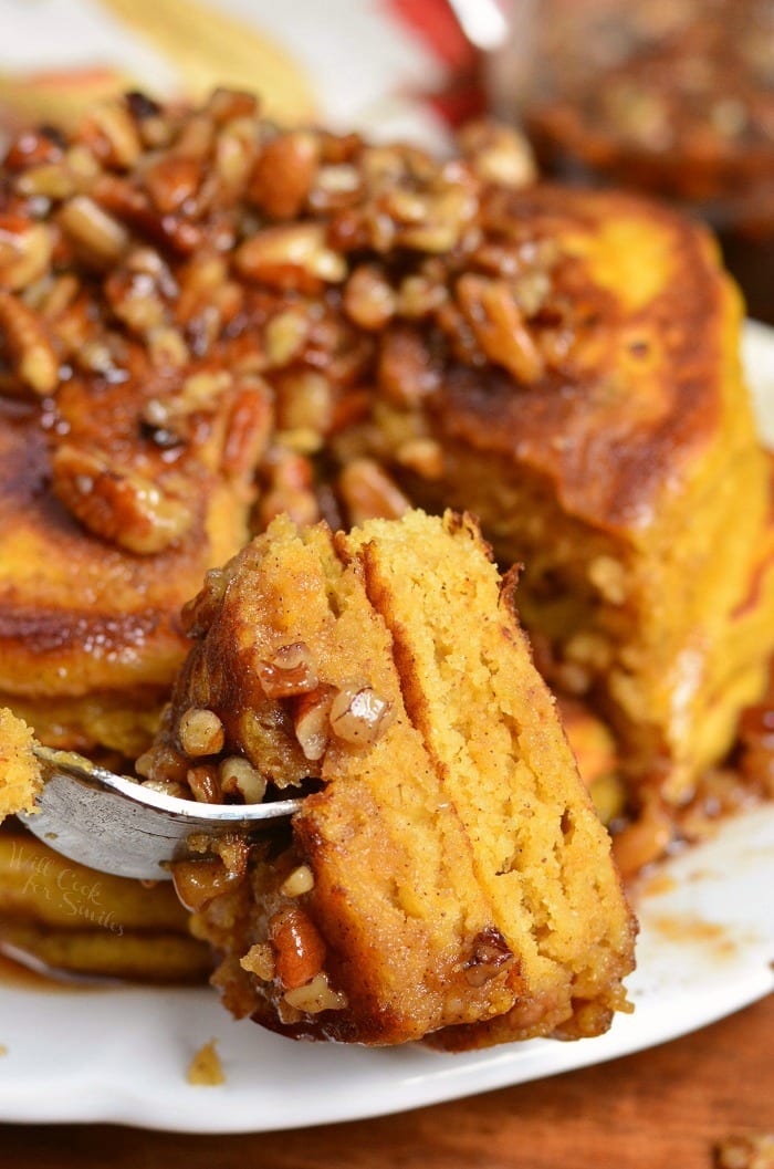 Homemade Pumpkin Pancakes with Cinnamon Pecan Syrup on a plate and bite on a fork 