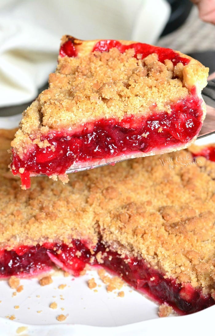 lifting an Apple Cranberry Pie slice out of a pie pan 