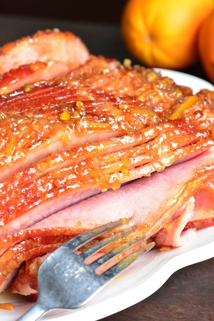 Baked Ham with Orange Honey Ham Glaze on a serving platter with a fork 