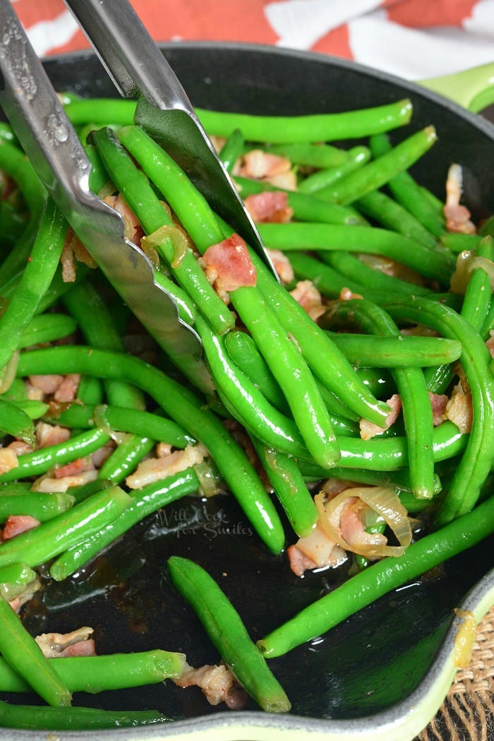 Green Beans with Bacon and Onion in a pan with tongs 