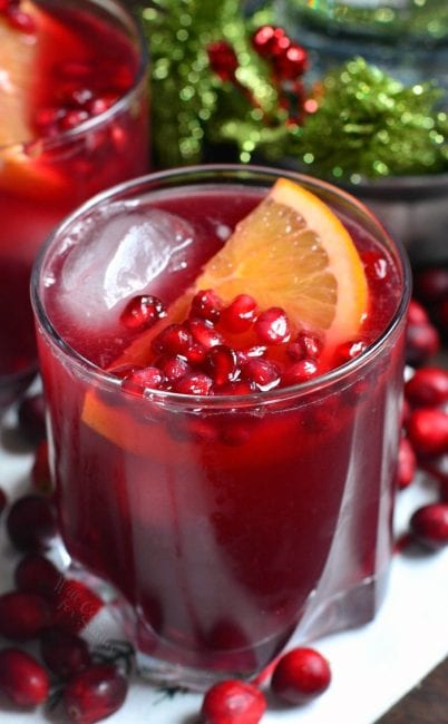 closeup of deep red cocktail in a glass with orange slide