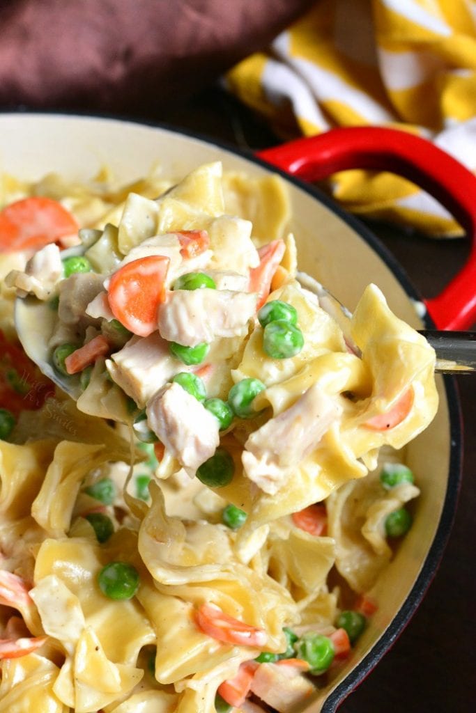 scooping out some noodles from the pan with a ladle.