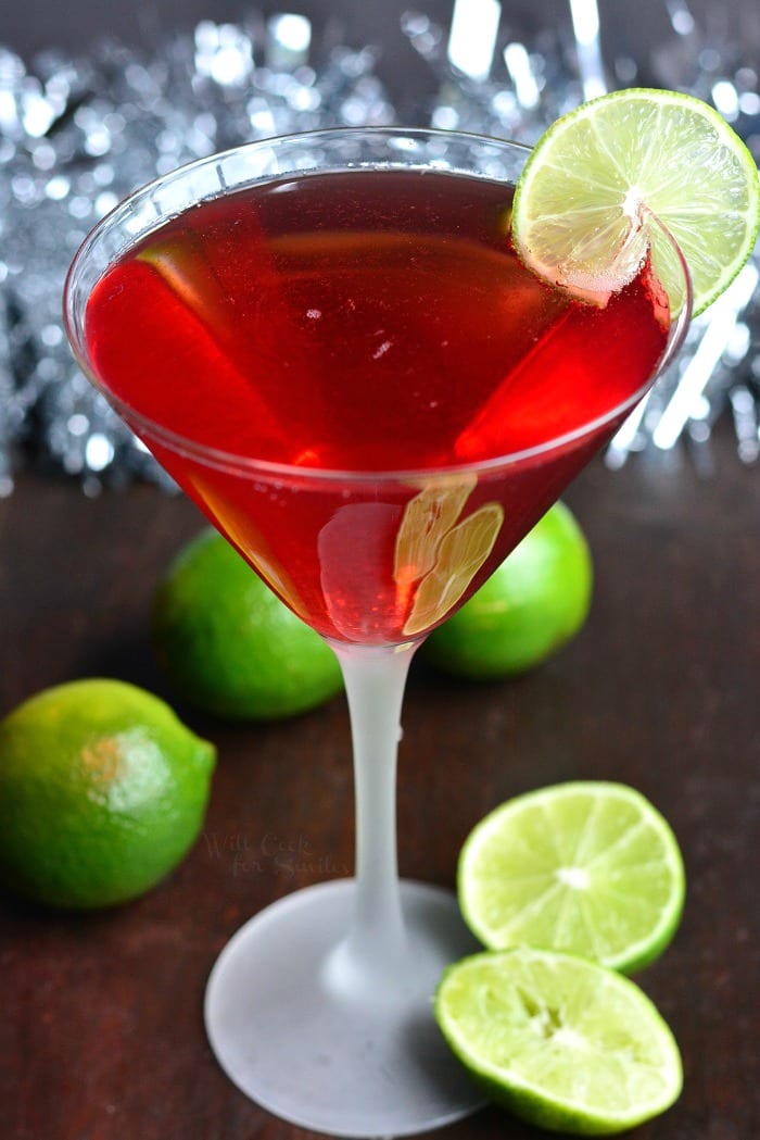 Cosmopolitan cocktail champagne cocktail in a martini glass on a cutting board with limes