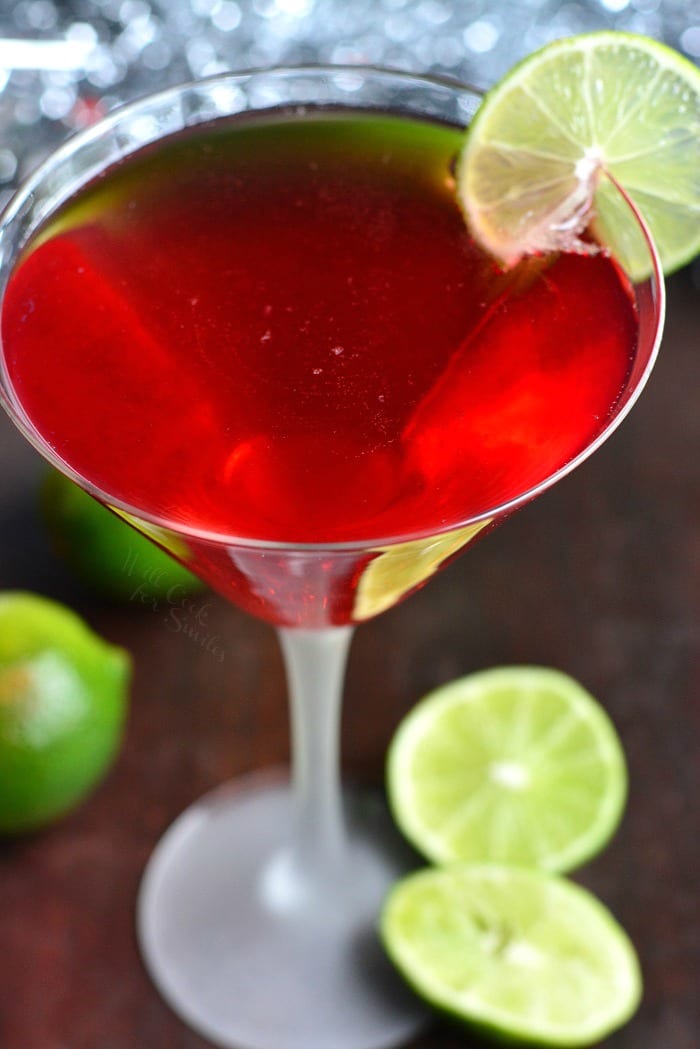 Cosmopolitan cocktail champagne cocktail in a martini glass on a cutting board with limes