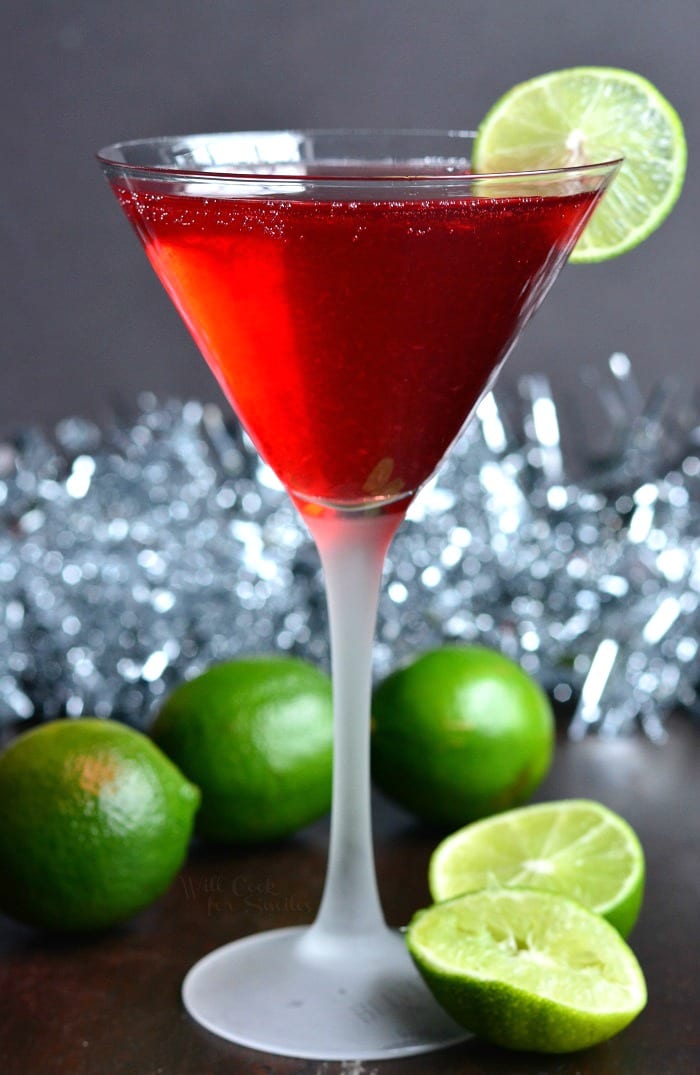 Cosmopolitan cocktail champagne cocktail in a martini glass on a cutting board with limes