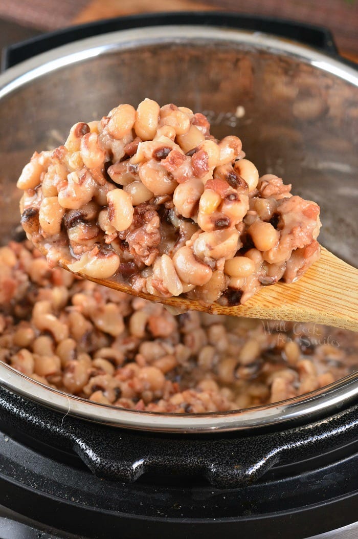 spooning out Black Eyed Peas with Bacon on a wooden spoon 