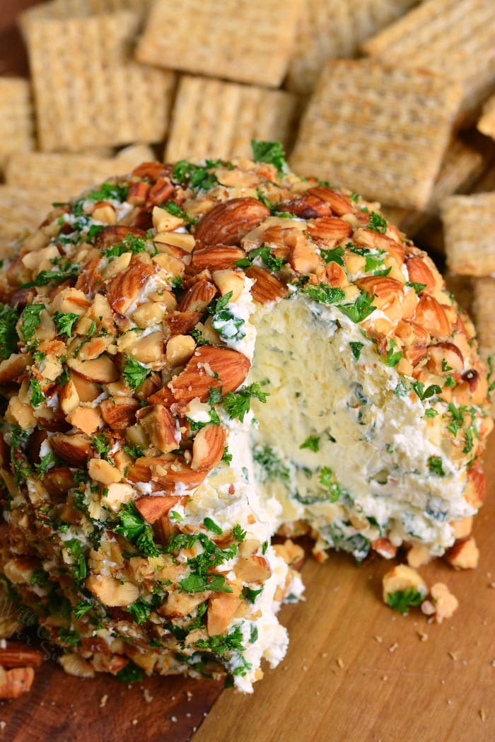 Ranch Cheddar Cheese Ball with a piece missing on a cutting board with wheat thins 