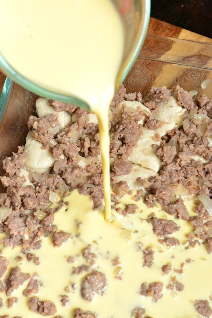 adding the egg mixture to the sausage and biscuits in the dish.