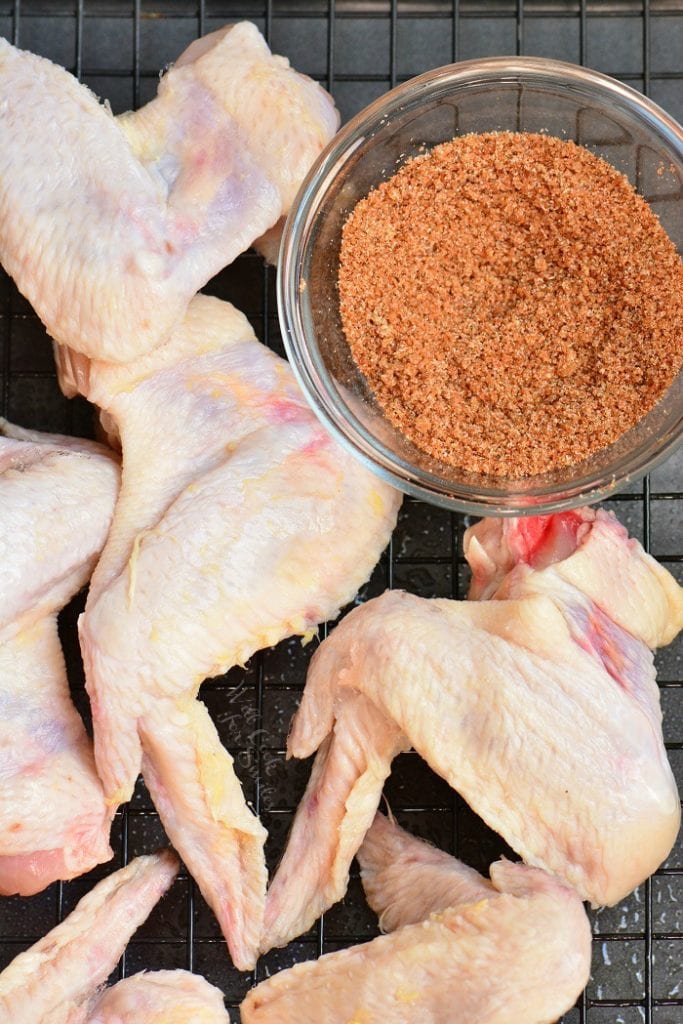 chicken wings on a wire rack next to dry rub.