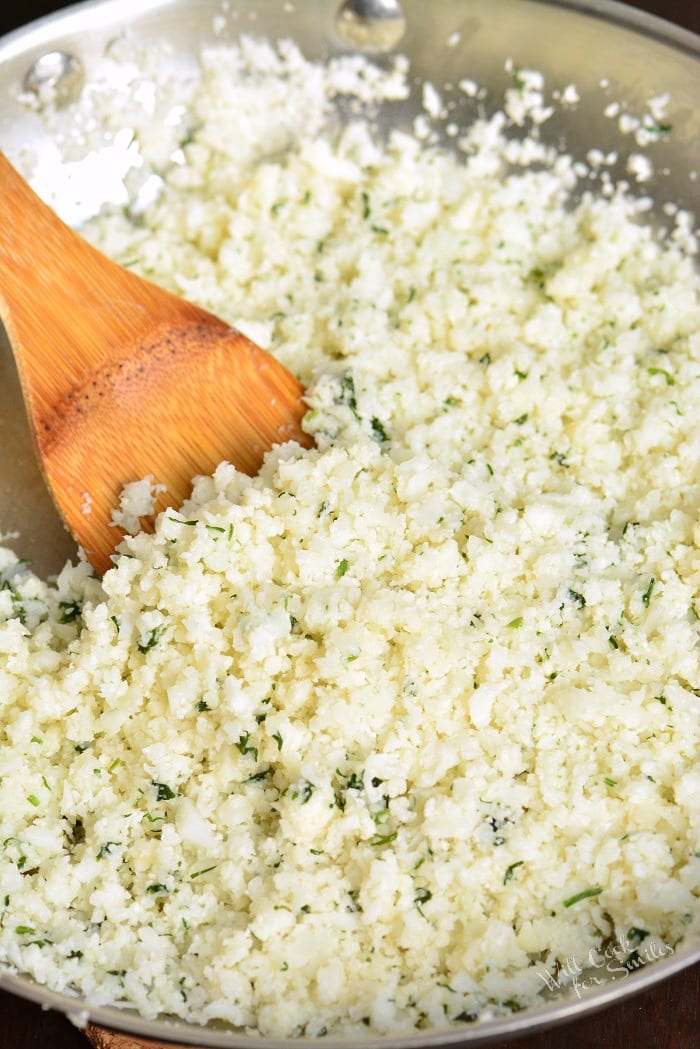 Cauliflower rice with a metal bowl and a wooden spoon 