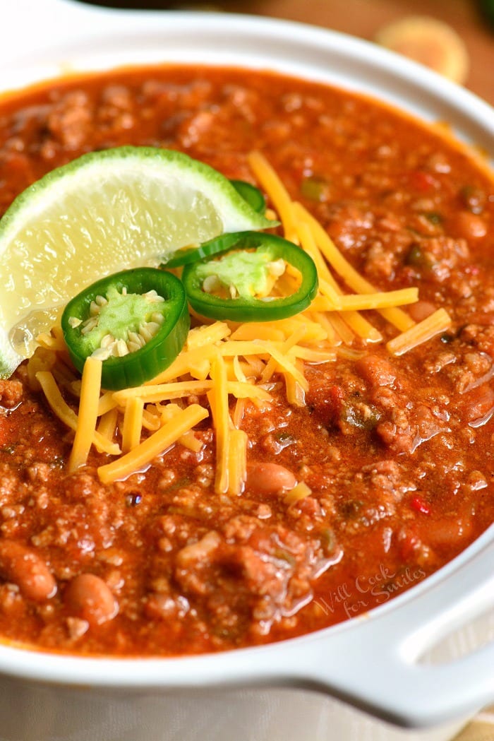 Beef Chili Recipe in a bowl with jalapenos, cheese, and lime on top