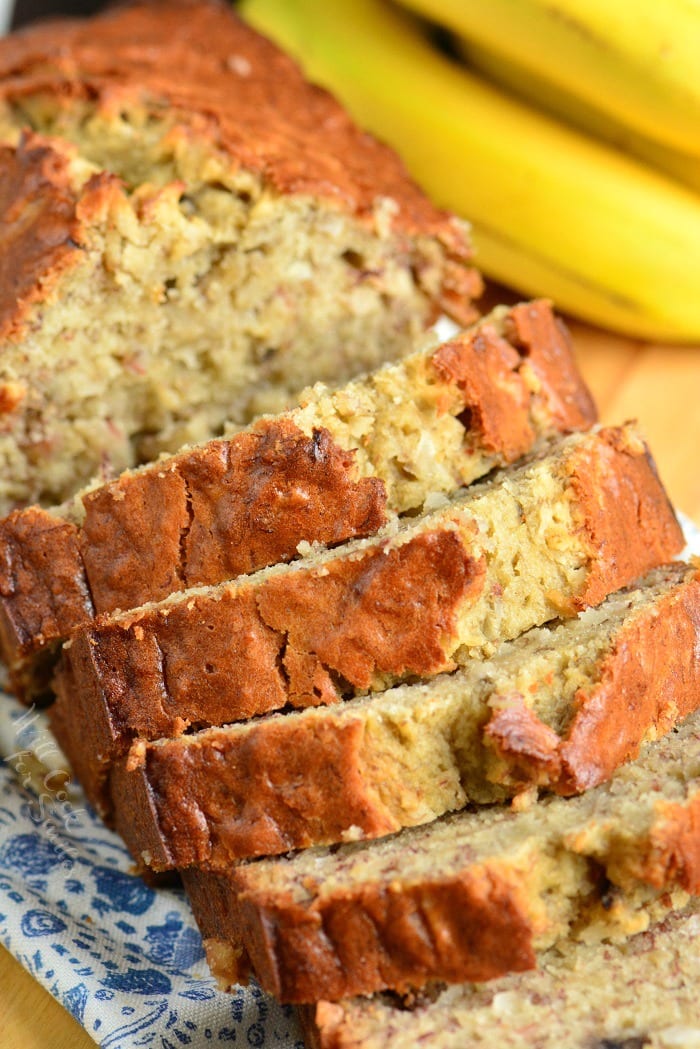 Banana Bread with Coconut sliced on a cutting board with bananas 