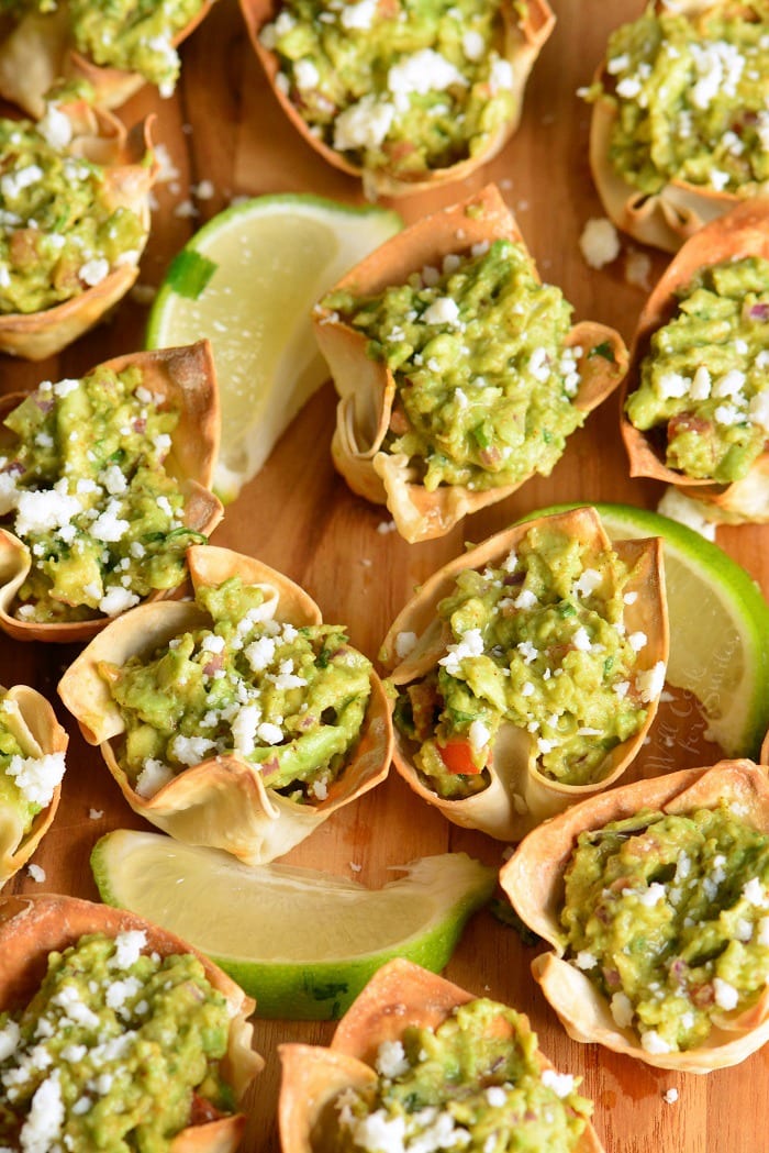 Guacamole in Crispy Cups on a cutting board with slices of lime 