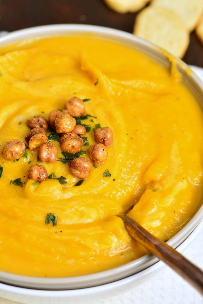 Butternut Squash Soup in a bowl with chick peas on top with a spoon 