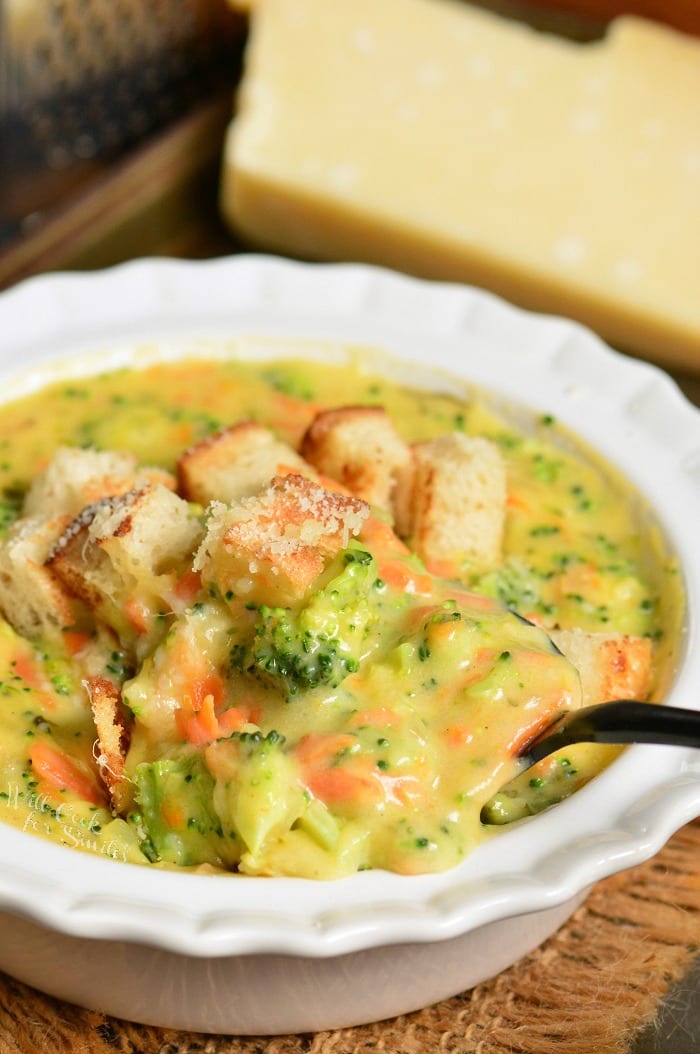 Broccoli Cheese Soup in a bowl with a spoon in it on a wood table 