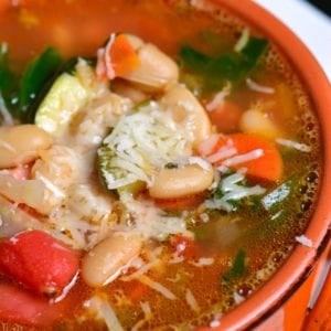 top view of minestrone soup in a red bowl.