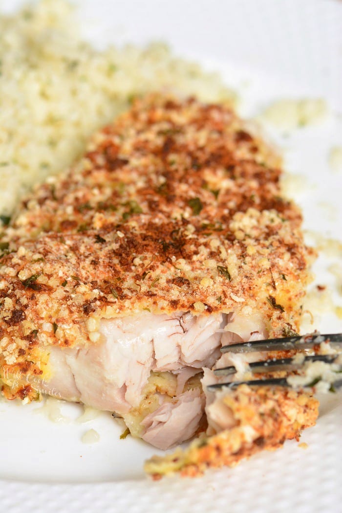 Baked Mahi Mahi on a plate with a fork taking a piece out with rice 